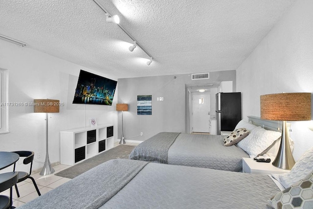 tiled bedroom with stainless steel fridge, rail lighting, and a textured ceiling