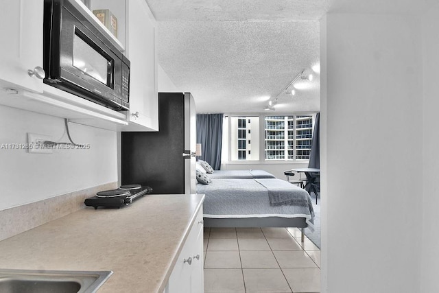 tiled bedroom featuring stainless steel refrigerator, rail lighting, and a textured ceiling