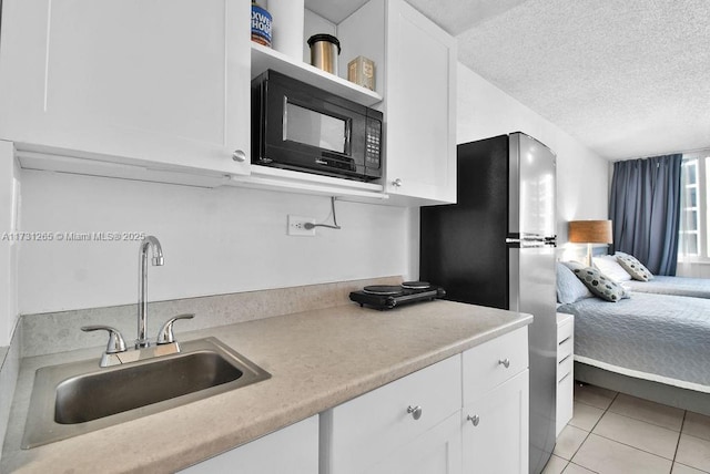 kitchen with sink, stainless steel refrigerator, white cabinets, and light tile patterned flooring