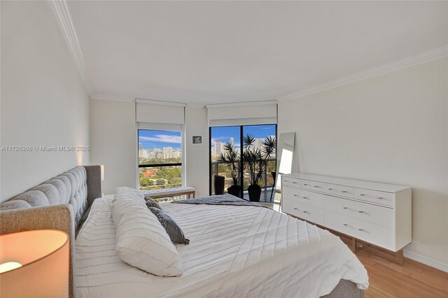 bedroom featuring crown molding, light hardwood / wood-style flooring, and access to outside