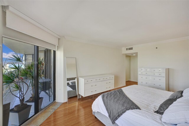 bedroom with hardwood / wood-style flooring, crown molding, and access to outside