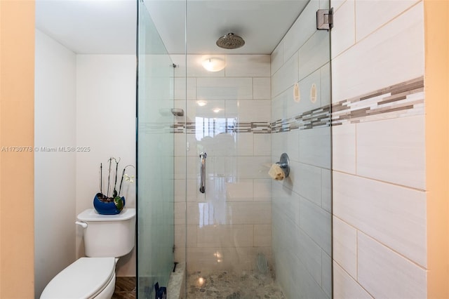 bathroom with a shower with shower door and toilet