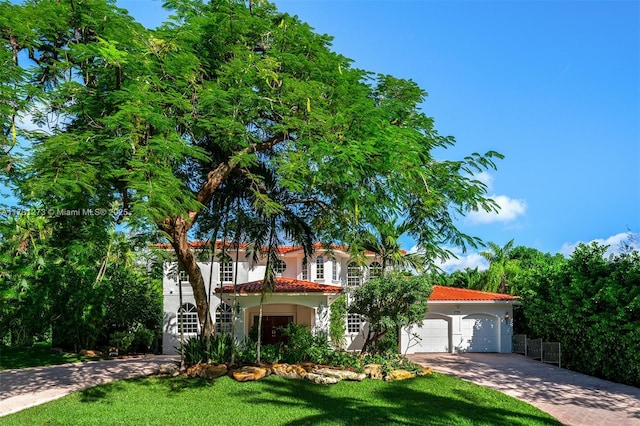 mediterranean / spanish-style house with a garage and a front lawn