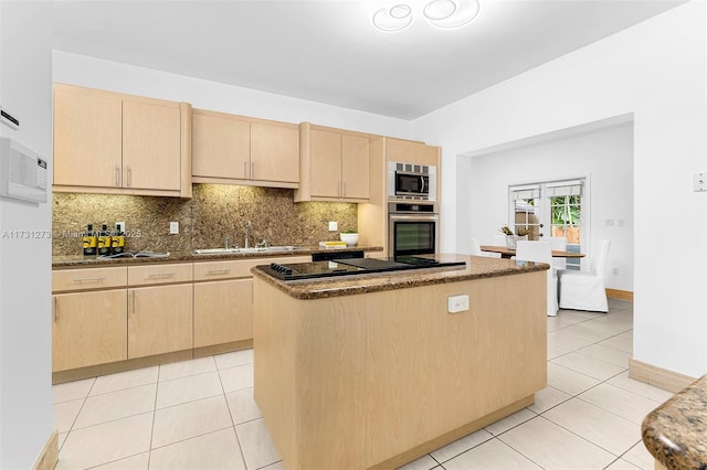 kitchen with sink, stainless steel appliances, a center island, dark stone counters, and light brown cabinets