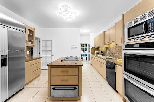 kitchen with sink, light tile patterned floors, black appliances, a kitchen island, and light brown cabinetry