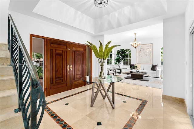 foyer entrance featuring a raised ceiling and a chandelier