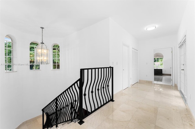 hallway featuring an inviting chandelier and plenty of natural light