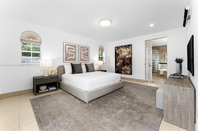 bedroom with ensuite bathroom and light tile patterned floors