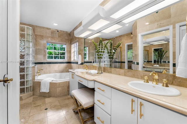 bathroom featuring tile patterned floors, vanity, tile walls, and tiled tub