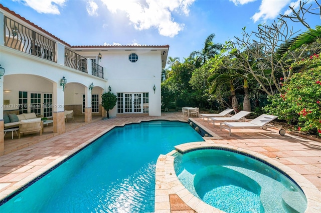 view of swimming pool with an in ground hot tub, outdoor lounge area, a patio area, and french doors