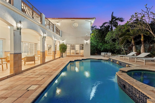 pool at dusk with a patio area and french doors