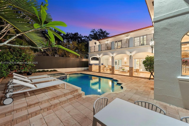 pool at dusk featuring french doors, an in ground hot tub, and a patio area