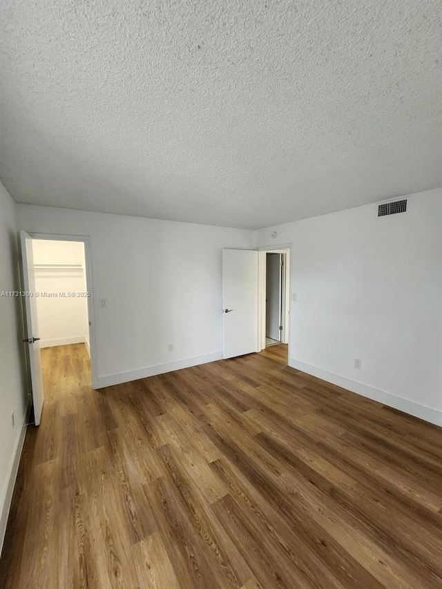 spare room featuring hardwood / wood-style floors and a textured ceiling