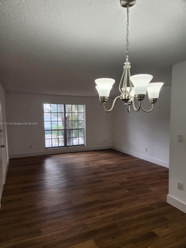 unfurnished room with an inviting chandelier, dark hardwood / wood-style flooring, and a textured ceiling