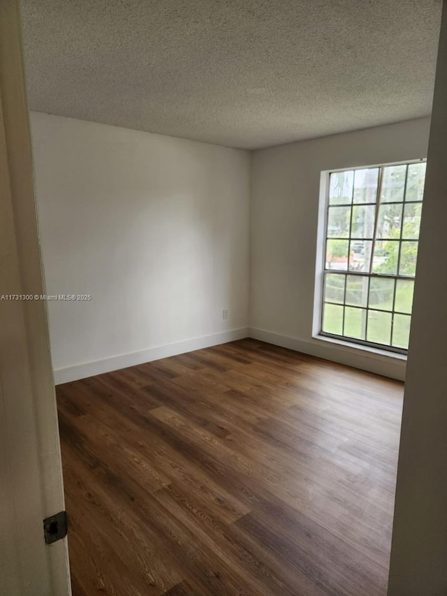 spare room with dark hardwood / wood-style floors and a textured ceiling