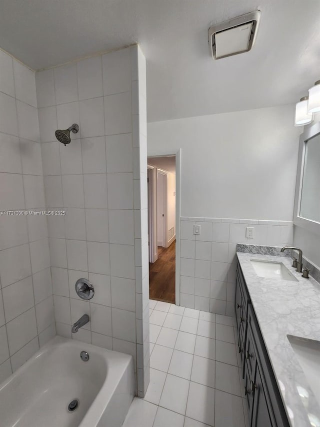 bathroom with tile walls, vanity, tile patterned flooring, and tiled shower / bath combo