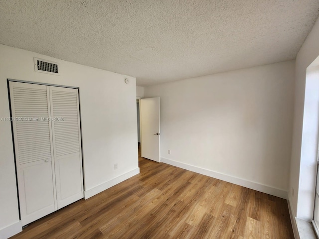 unfurnished bedroom with hardwood / wood-style flooring, a closet, and a textured ceiling