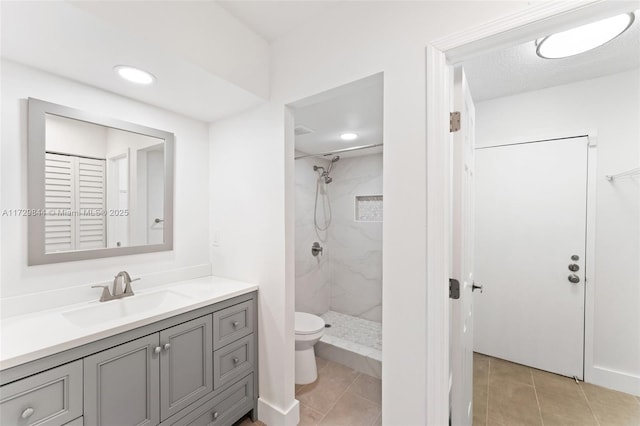 bathroom featuring tiled shower, vanity, toilet, and tile patterned floors