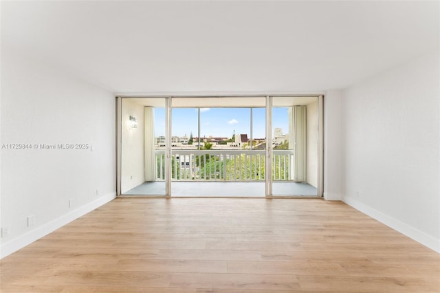 spare room featuring a wealth of natural light, light hardwood / wood-style floors, and floor to ceiling windows