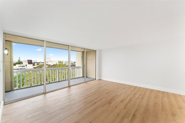 empty room with floor to ceiling windows and light wood-type flooring