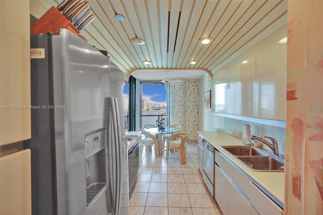 kitchen with appliances with stainless steel finishes, sink, wood ceiling, and light tile patterned floors