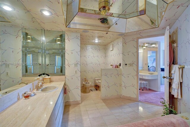 bathroom with a bidet, toilet, and vanity