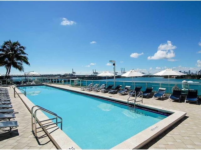 view of pool with a water view and a patio