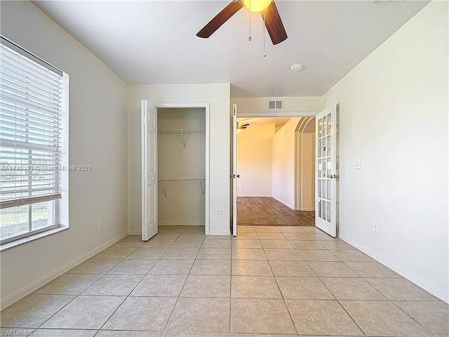 unfurnished bedroom with light tile patterned flooring, a closet, ceiling fan, and french doors