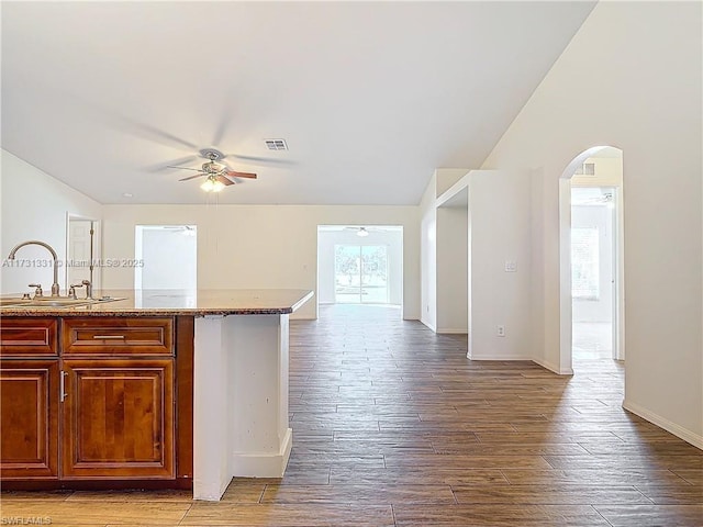 kitchen with light stone counters, sink, hardwood / wood-style flooring, and ceiling fan