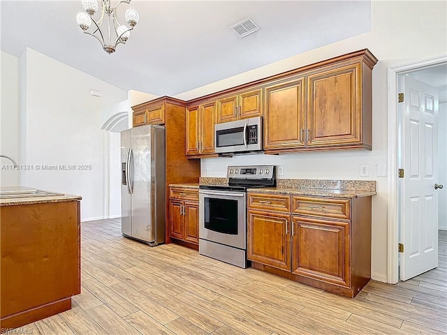 kitchen featuring appliances with stainless steel finishes, a chandelier, sink, and light wood-type flooring