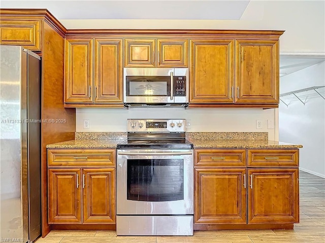 kitchen with light hardwood / wood-style flooring, stone counters, and appliances with stainless steel finishes