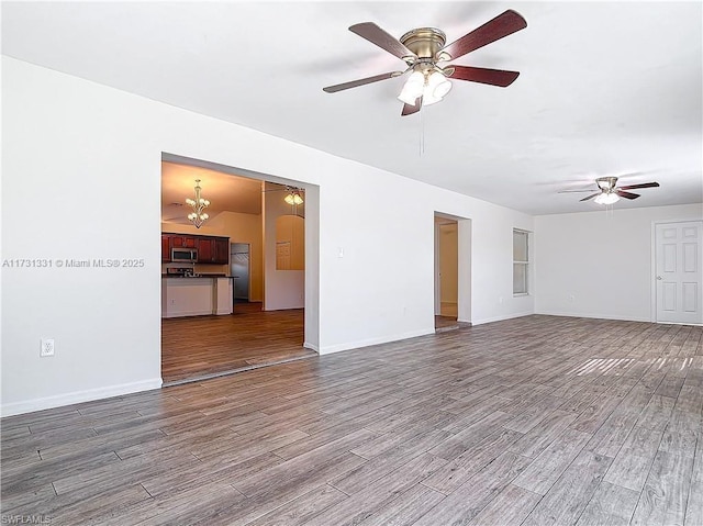 unfurnished living room featuring hardwood / wood-style flooring and ceiling fan with notable chandelier