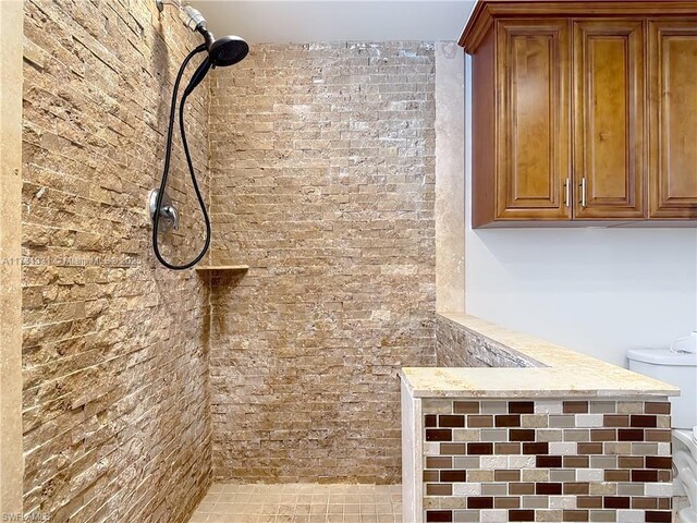 details with toilet and a tile shower