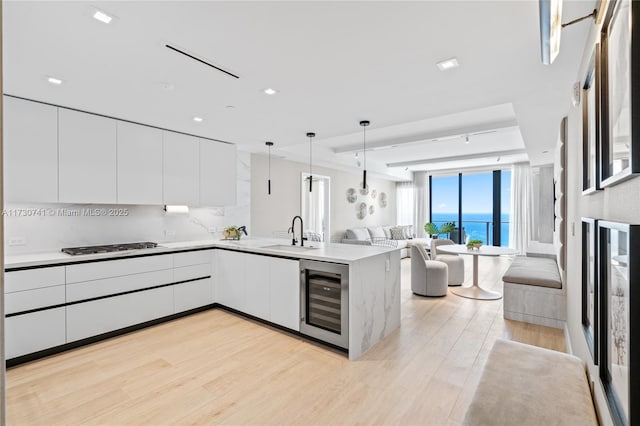 kitchen with beverage cooler, a peninsula, a sink, open floor plan, and modern cabinets