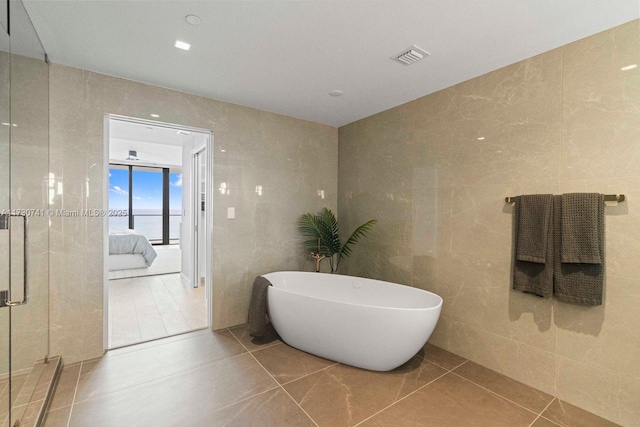 bathroom featuring tile patterned flooring, a water view, tile walls, and a wall of windows