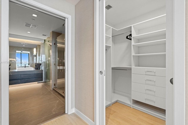 spacious closet with light hardwood / wood-style flooring