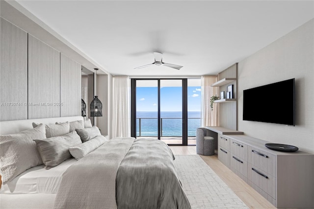 bedroom featuring light wood-style floors, access to exterior, a wall of windows, and a ceiling fan