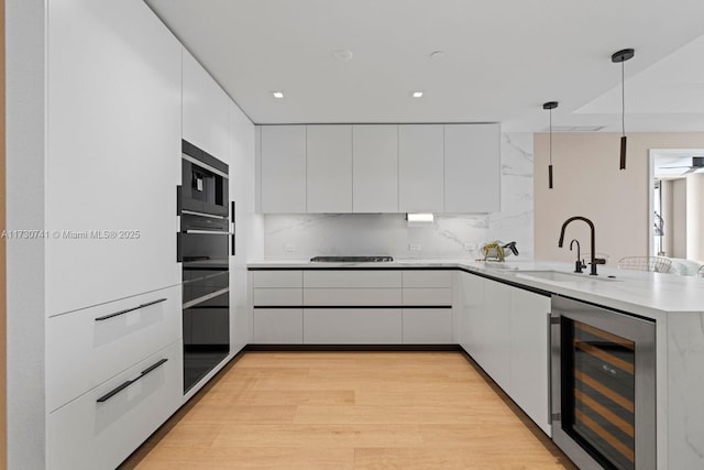 kitchen with beverage cooler, decorative light fixtures, kitchen peninsula, and white cabinets