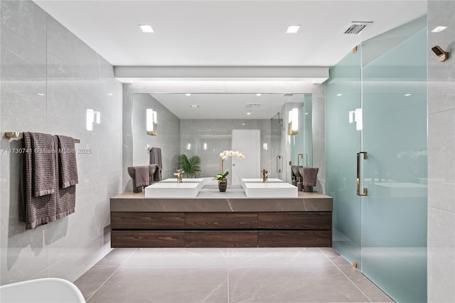 full bathroom with a stall shower, visible vents, tile walls, and a sink