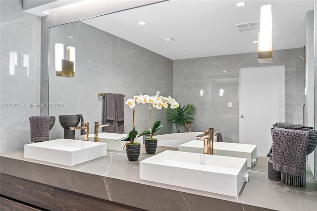 full bathroom featuring visible vents, a sink, and tile walls