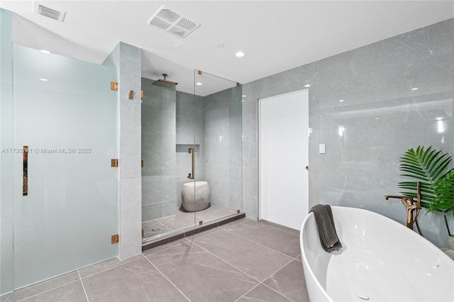 bathroom featuring a soaking tub, visible vents, tile walls, and a shower stall