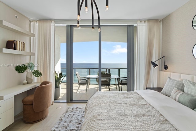 bedroom with expansive windows, a water view, built in desk, and access to exterior