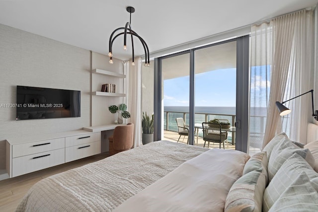 bedroom featuring floor to ceiling windows, a water view, access to outside, and light hardwood / wood-style flooring