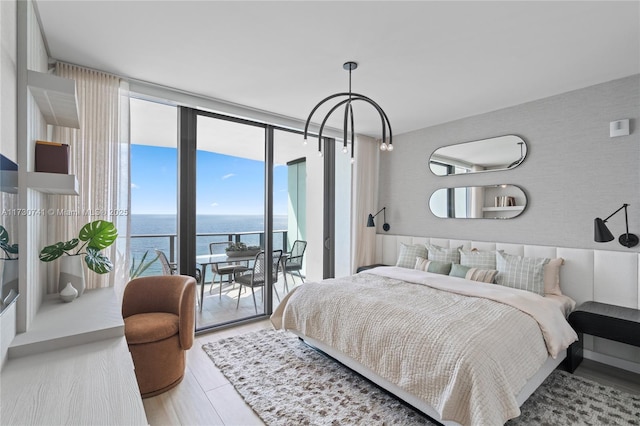 bedroom featuring a wall of windows, access to outside, a water view, and wood finished floors