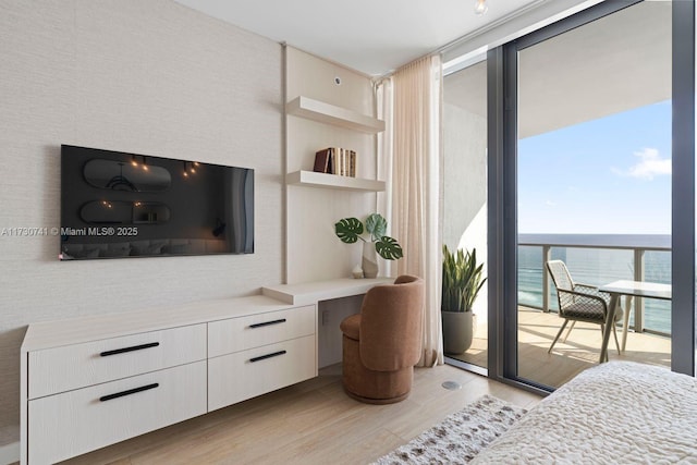 bedroom featuring a water view, built in desk, multiple windows, and access to outside