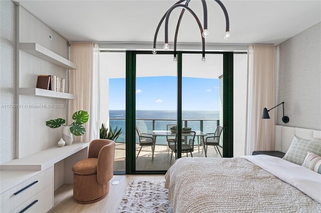 bedroom featuring built in desk, a water view, light wood-style flooring, and floor to ceiling windows