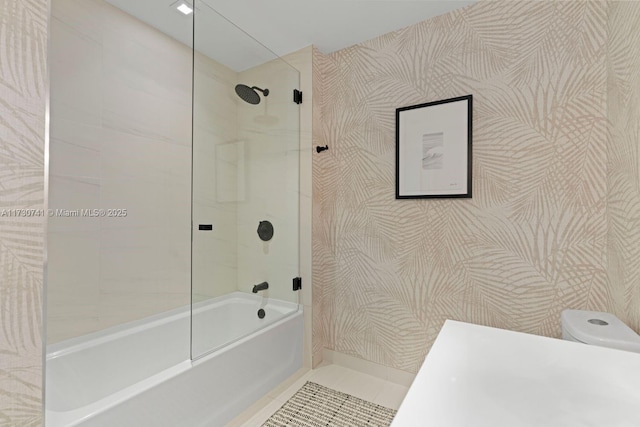 bathroom featuring tiled shower / bath, tile patterned floors, and toilet