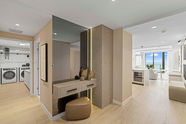 hallway with light hardwood / wood-style flooring, beverage cooler, independent washer and dryer, and a wall of windows