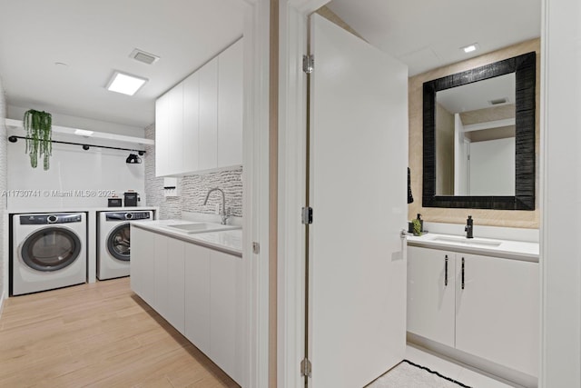 laundry area with separate washer and dryer, sink, and light wood-type flooring