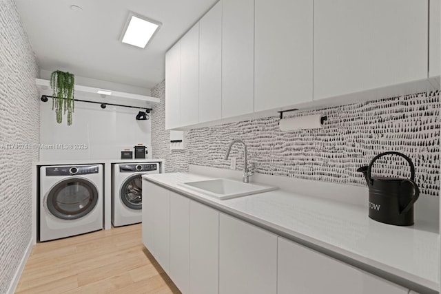 laundry room with cabinets, washer and clothes dryer, sink, and light wood-type flooring